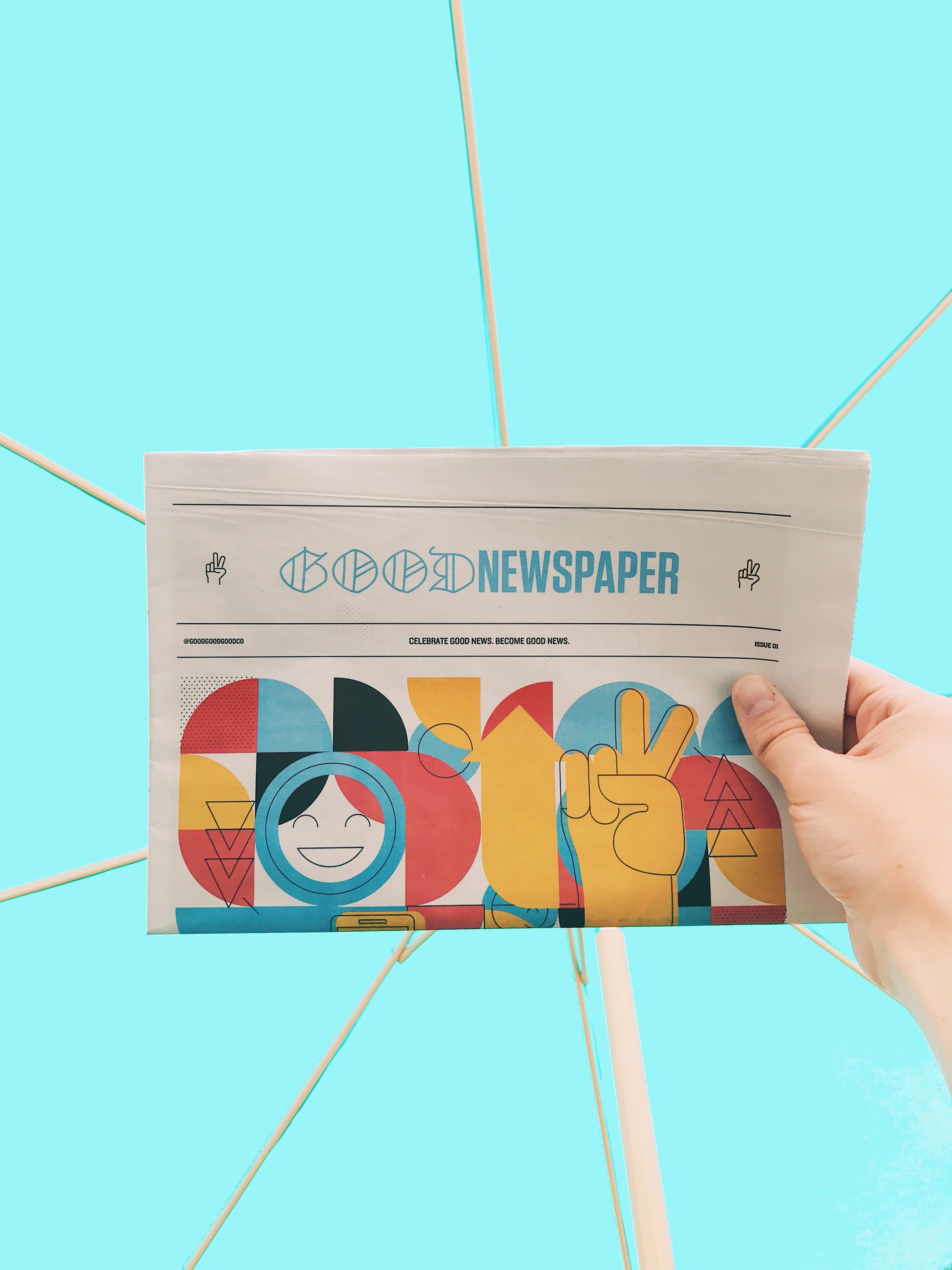 Hand holding colorful newspaper page in front of light blue background